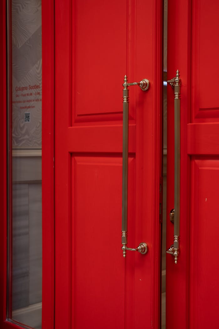 gallery-4 Close-up of a red double door featuring ornate metal handles, perfect for architectural themes.
