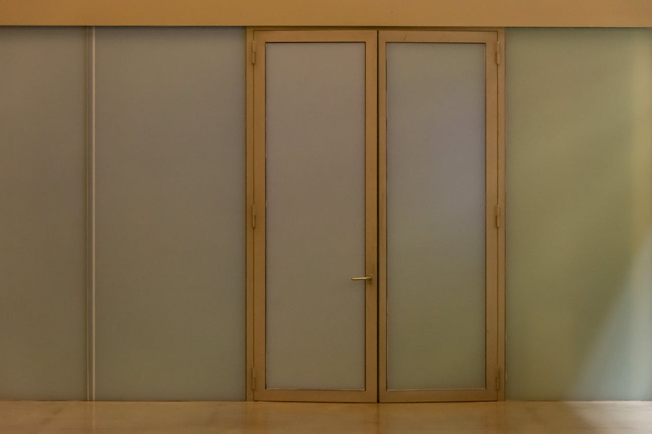 gallery-2 A minimalist beige door with frosted glass panels creating a modern aesthetic in an indoor setting.